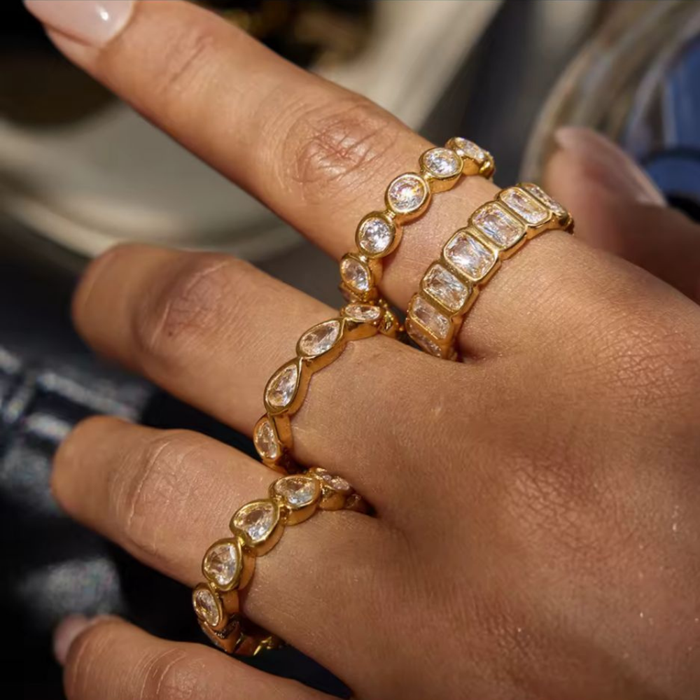 Close-up of a hand wearing multiple gold rings with gemstones.