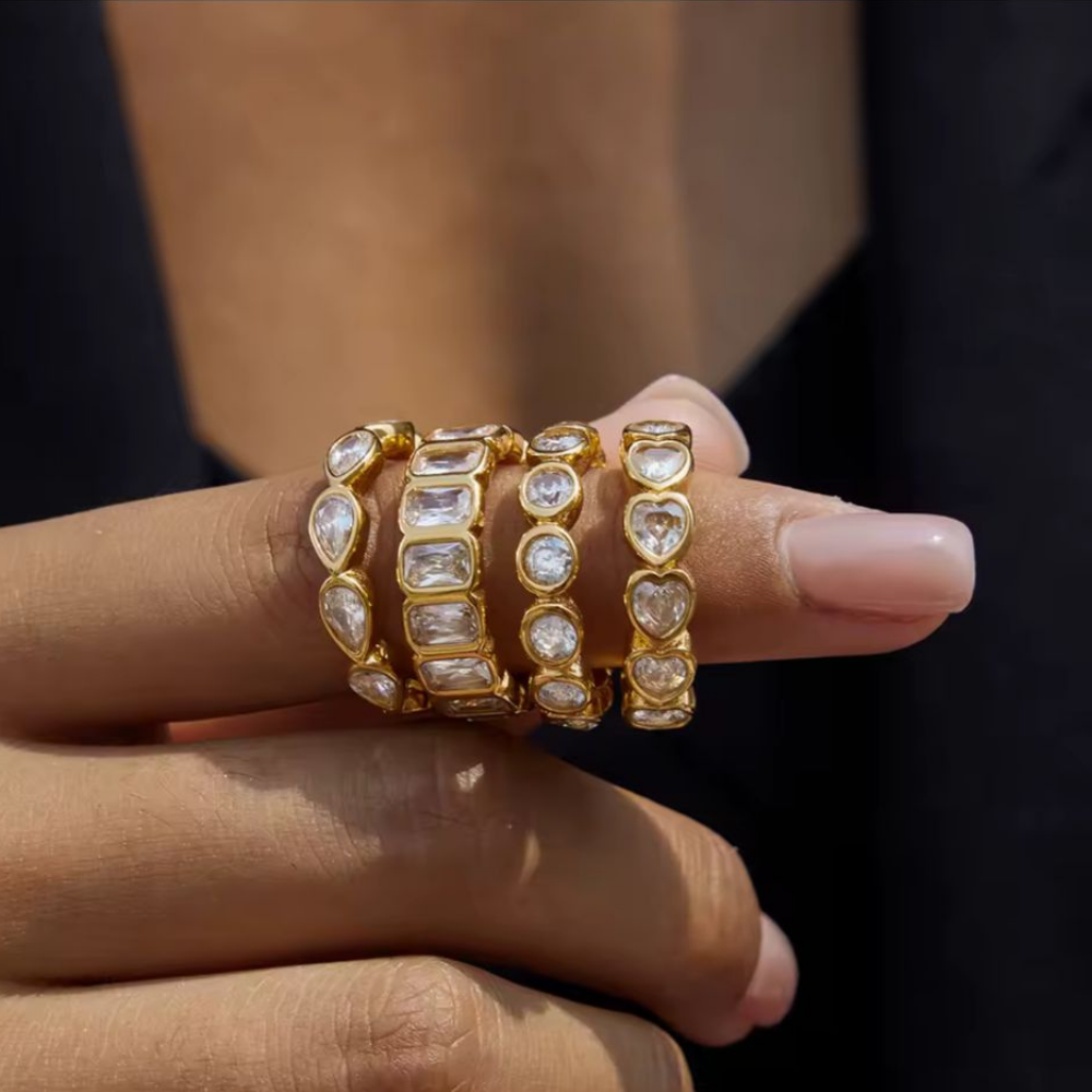 Gold and diamond-studded bracelets on a hand against a dark background