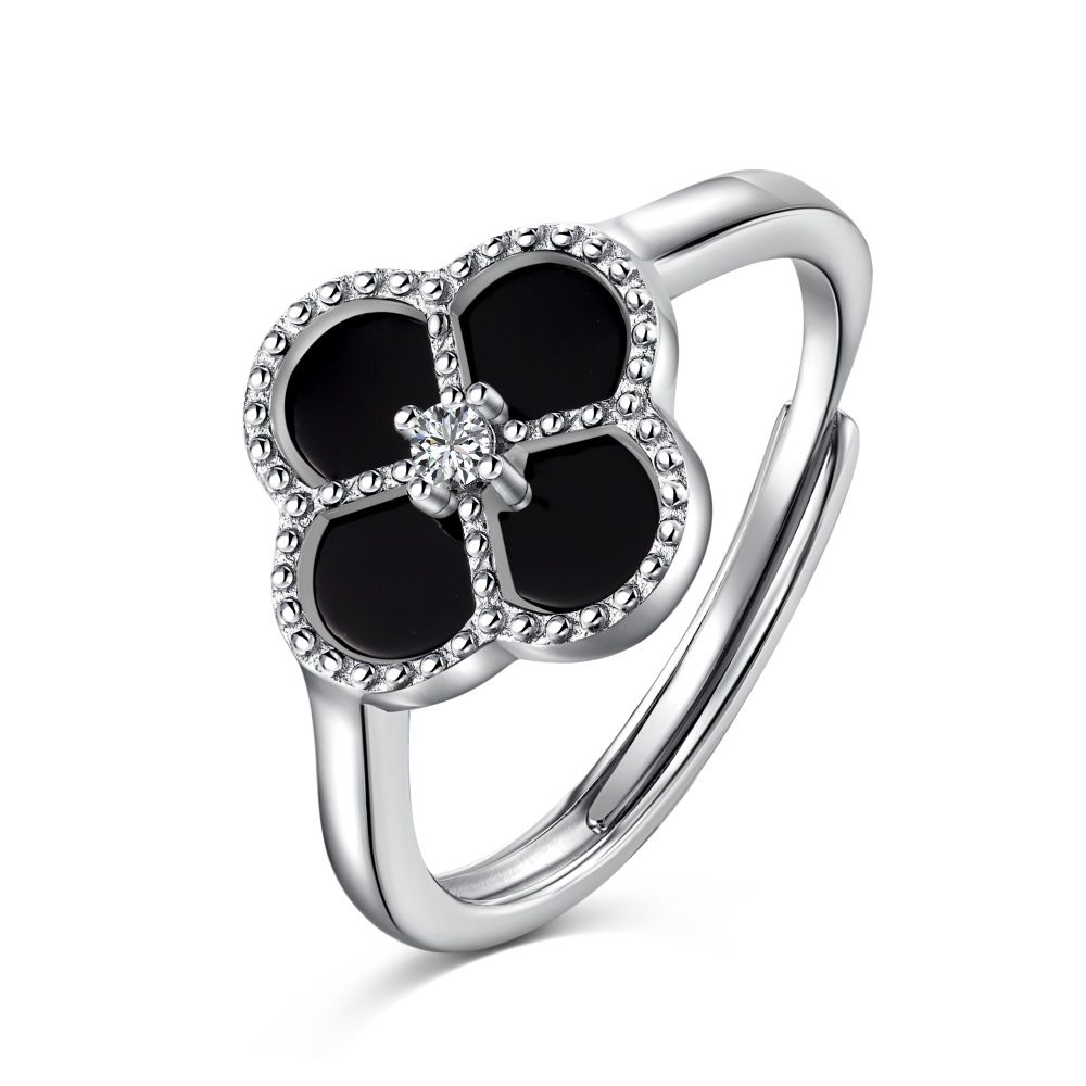 A sterling silver ring with a clover-shaped design, featuring a black and white zircon stone in the center, surrounded by a silver-colored band.