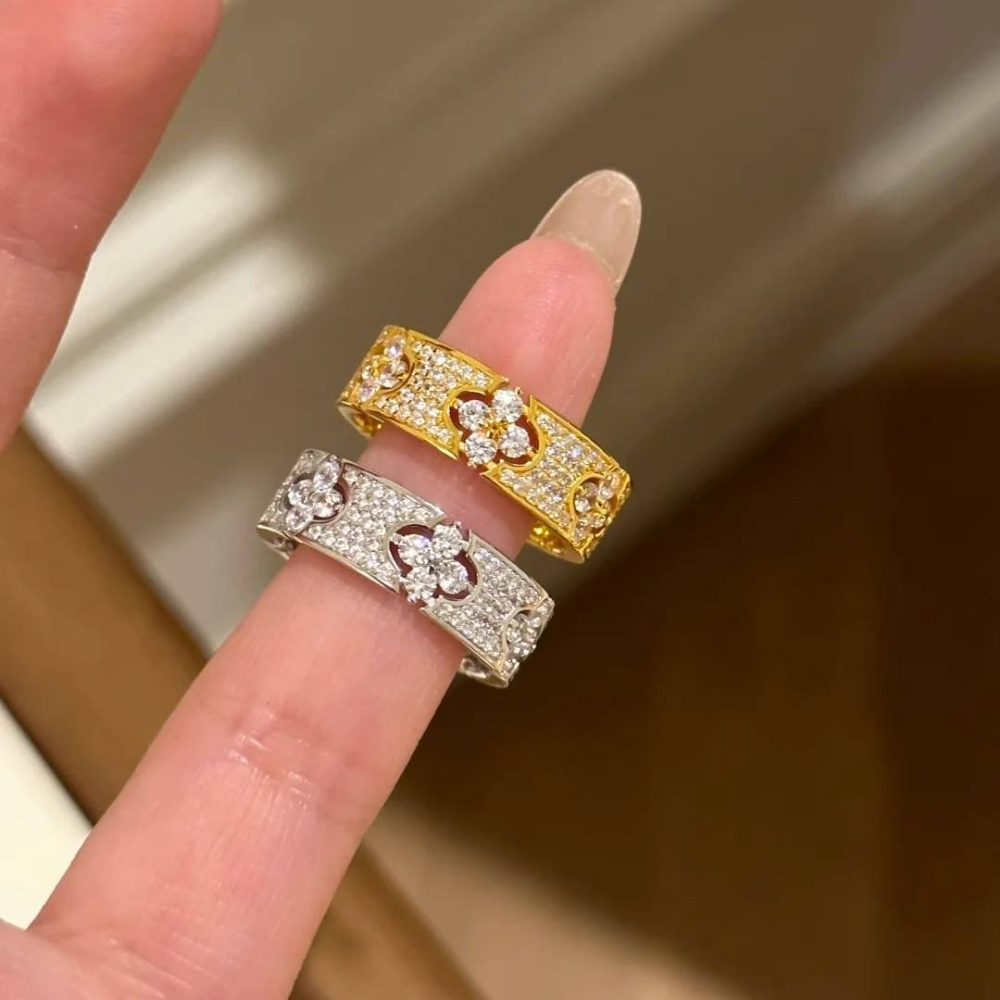 Gold and silver rings with gemstones on a finger against a neutral background