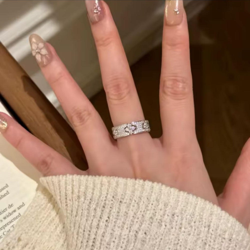 Hand wearing a diamond ring with a blurred background