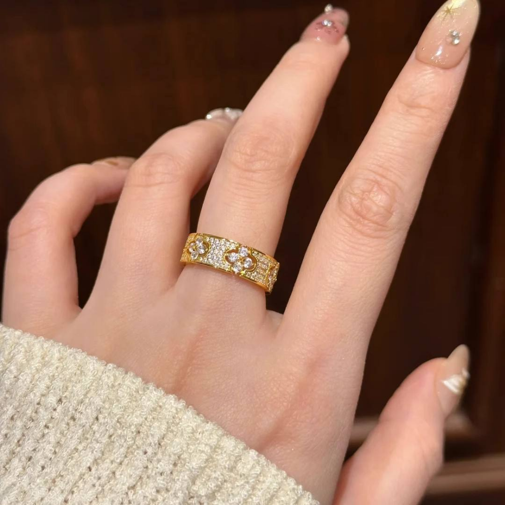 Gold ring with diamonds on a person's finger against a blurred background