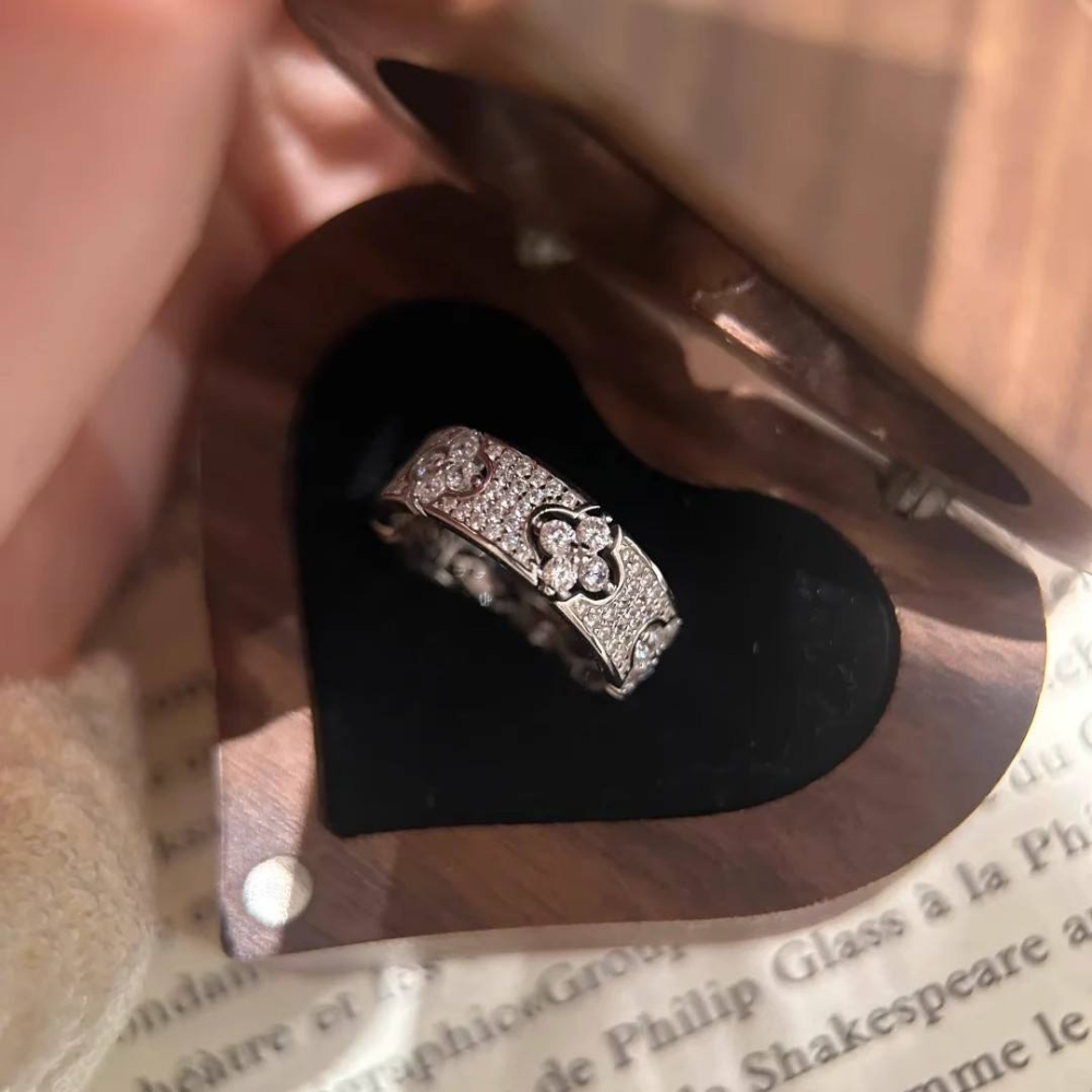 Silver ring with a floral design on a black heart-shaped cushion