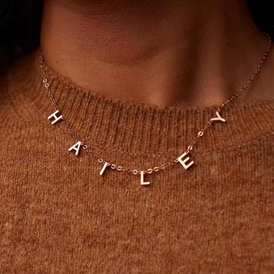 Necklace with 'HALE' letters on a brown sweater