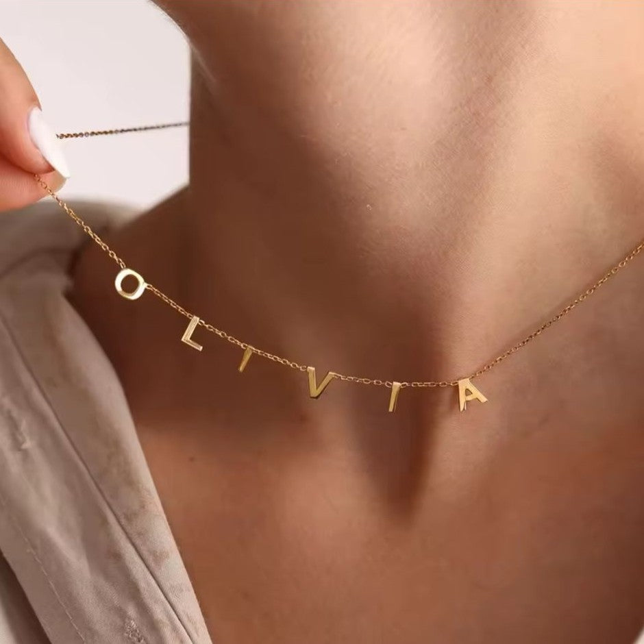 Gold necklace with 'OLIVIA' pendant on a person's neck