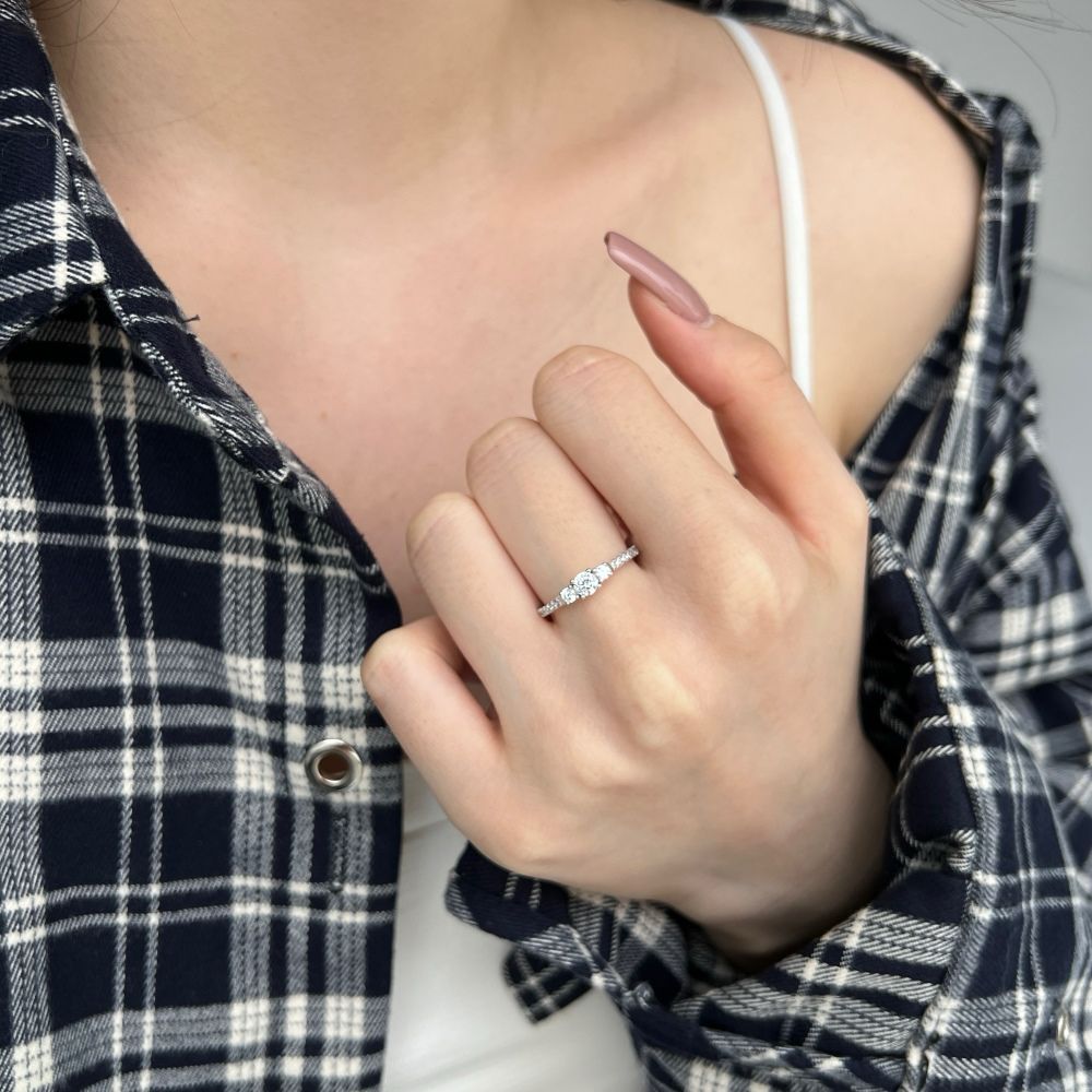 A dainty engagement ring featuring a central cubic zirconia stone with smaller stones on the band, set in a silver-tone mounting.