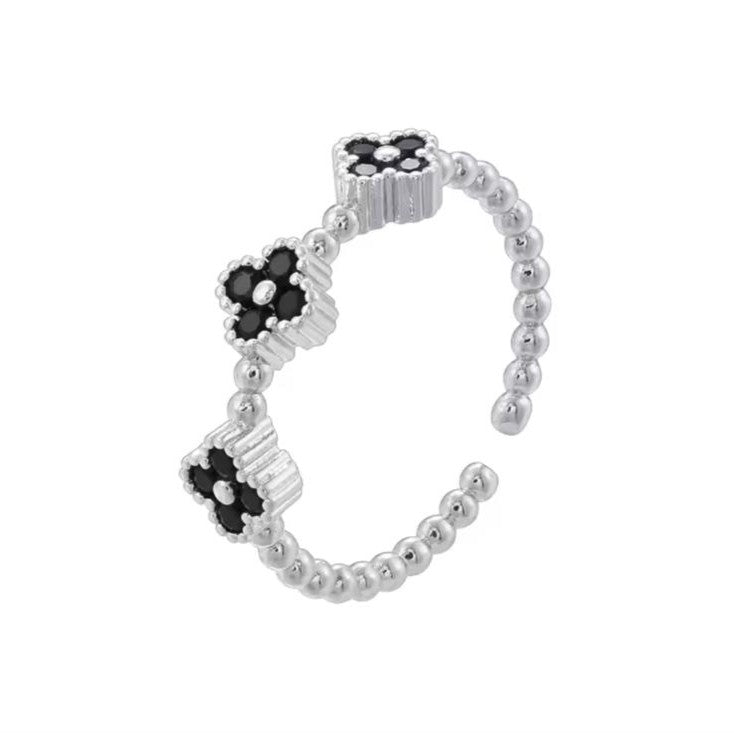 Silver beaded ring with black flower-shaped beads on a white background