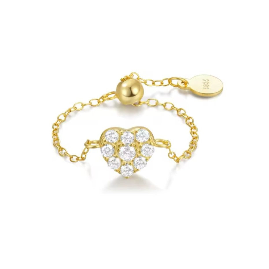 A gold-colored adjustable chain ring with a sparkling diamanté heart centerpiece.