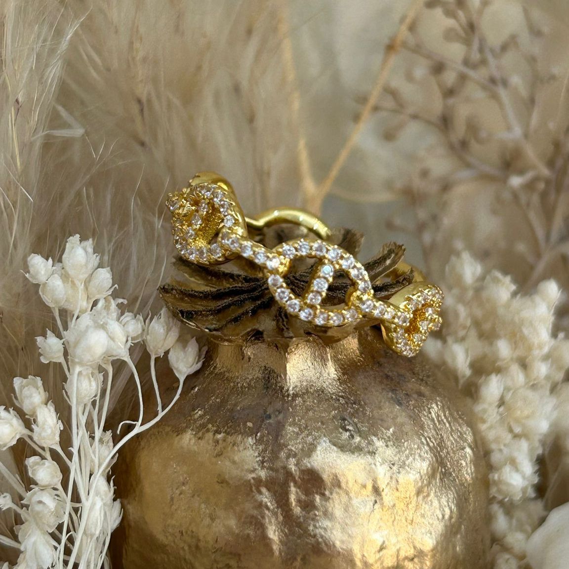 Gold ring with diamond accents on a gold vase against a natural background