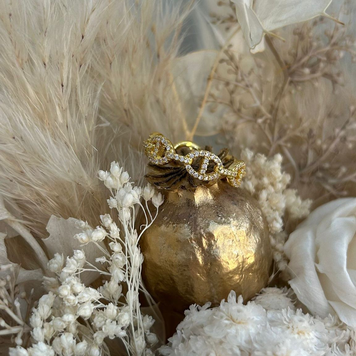 Gold ring with diamond accents on a gold vase against a natural background