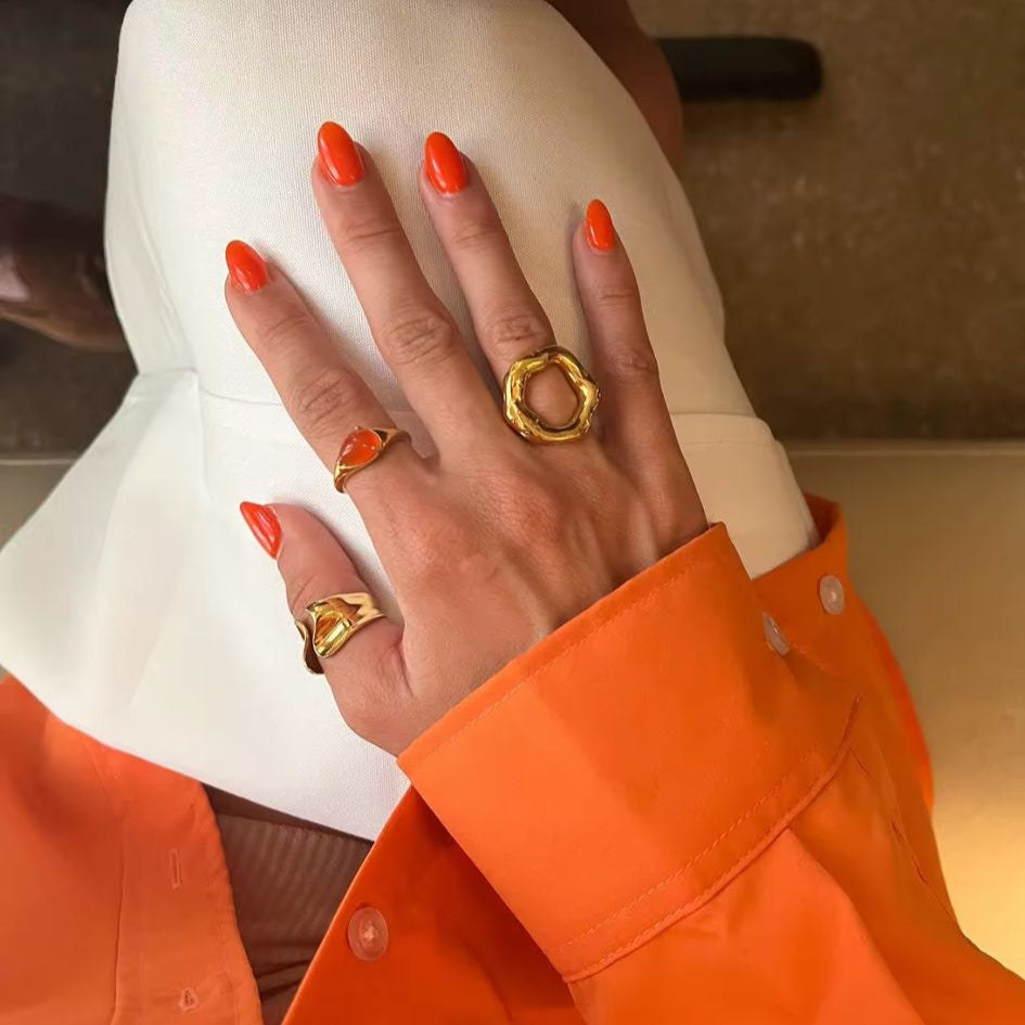 A gold metal hollow circle ring with an adjustable open design, displayed on a women's hand with blurred  background.