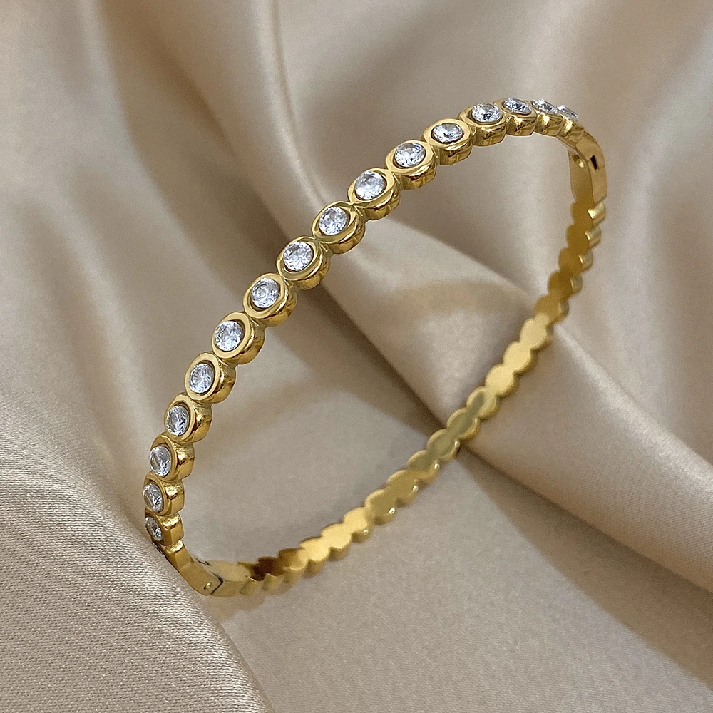 Gold bracelet with embedded diamonds on a beige fabric background