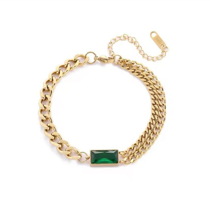 Gold chain bracelet with a green gemstone on a white background