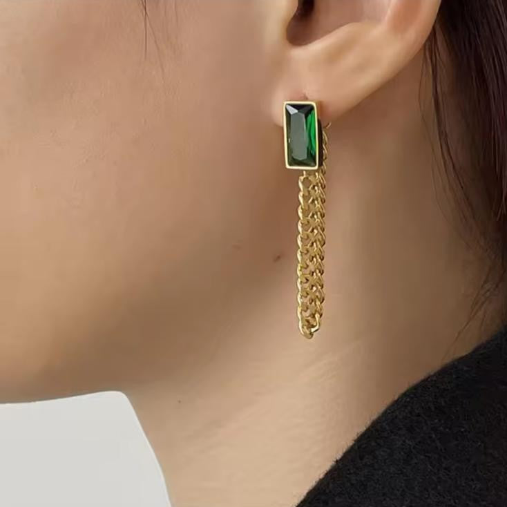 Gold chain earring with a green gemstone worn by a person