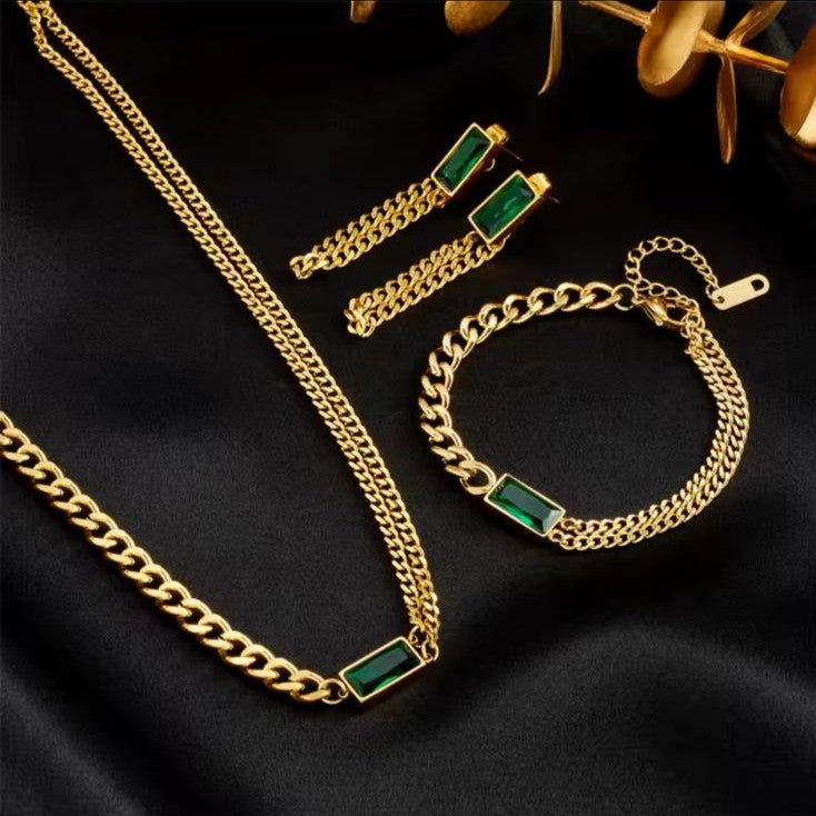 Gold jewelry set with green gemstones on a black background