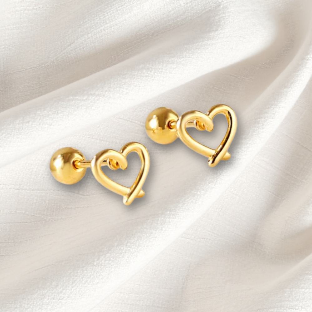 Gold heart-shaped earrings on a white fabric background