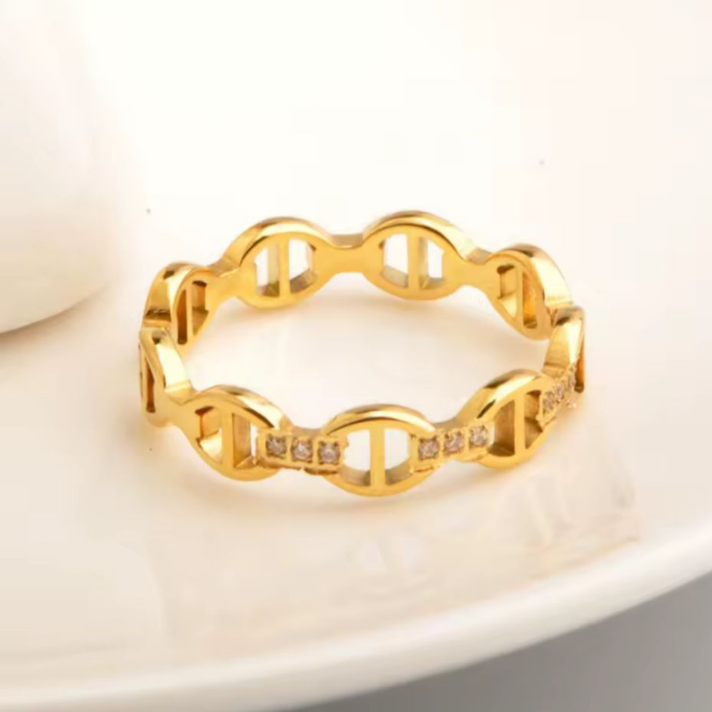 Gold chain-style ring with small diamonds on a beige background