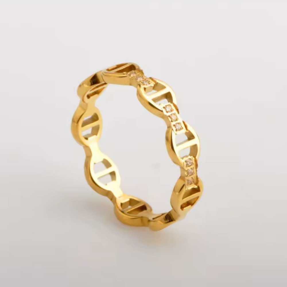 Gold chain-style ring with small diamonds on a beige background