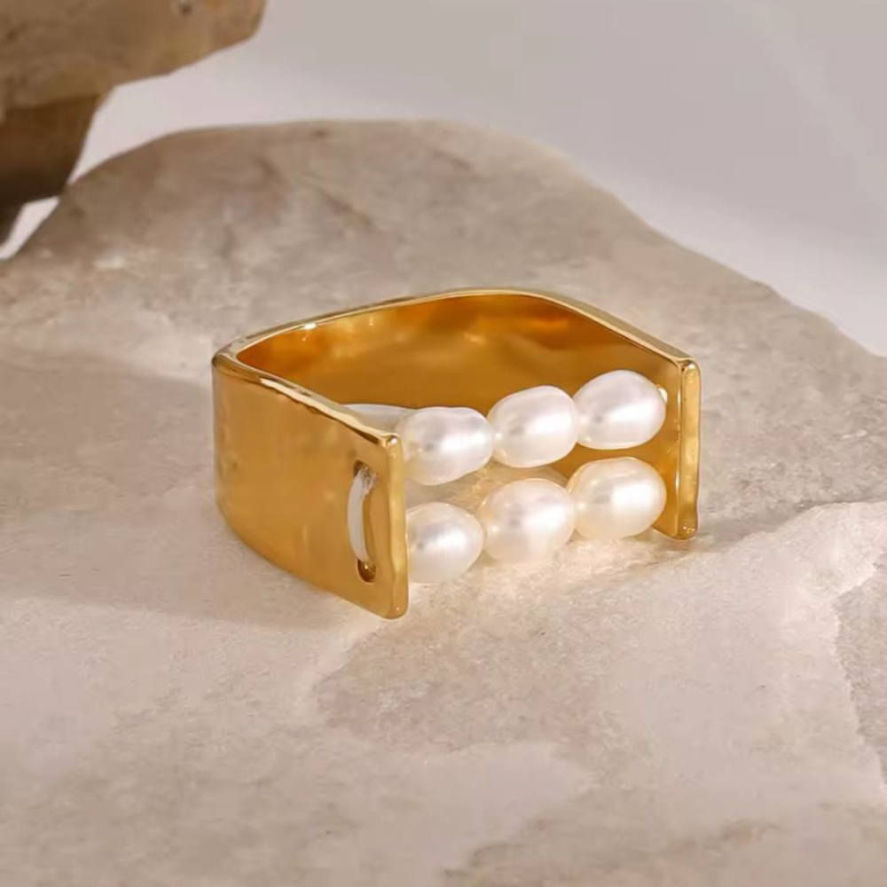 Gold ring with pearls on a textured surface