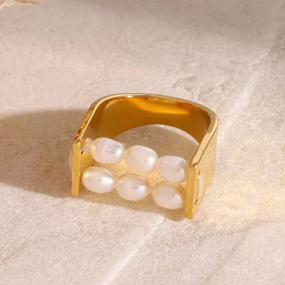 Gold ring with pearls on a beige fabric background