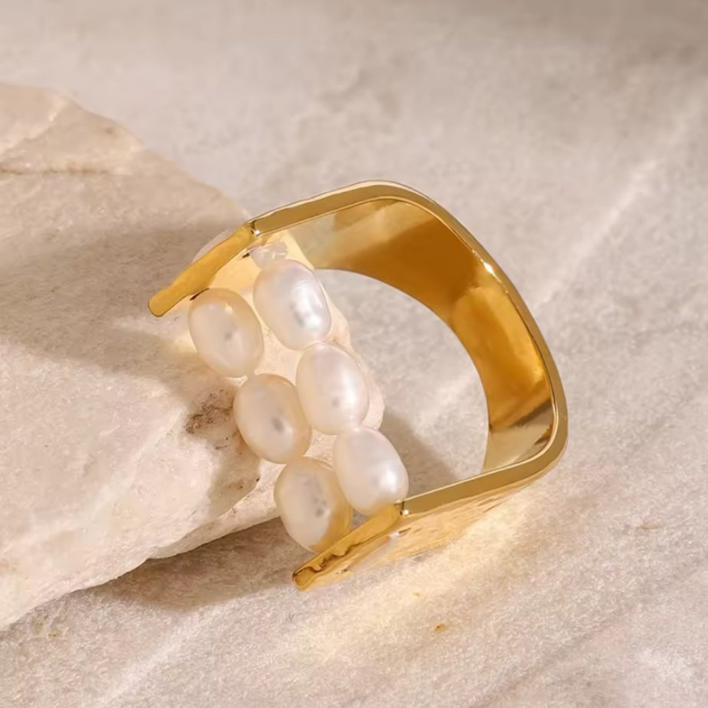 Gold ring with pearls on a beige stone background