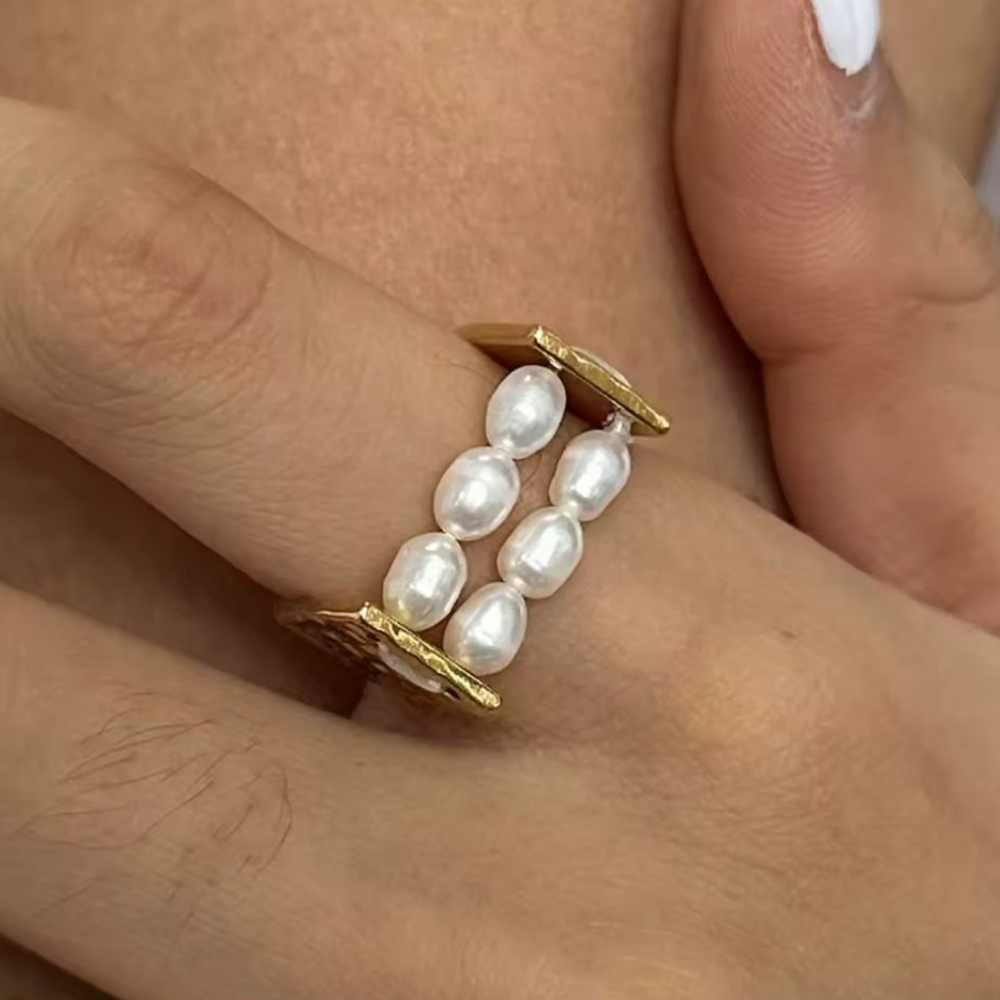 Hand wearing a pearl ring with a blurred background
