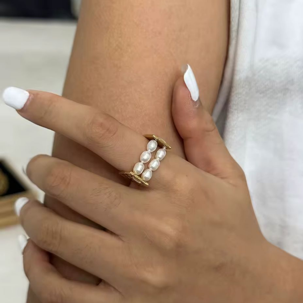 Hand wearing a pearl ring with a blurred background