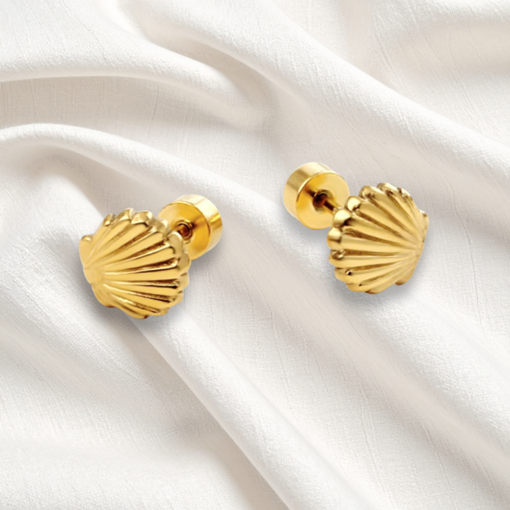 Gold shell-shaped earrings on a white fabric background