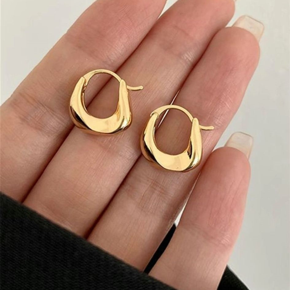A pair of gold-colored hoop earrings with a curved design.
