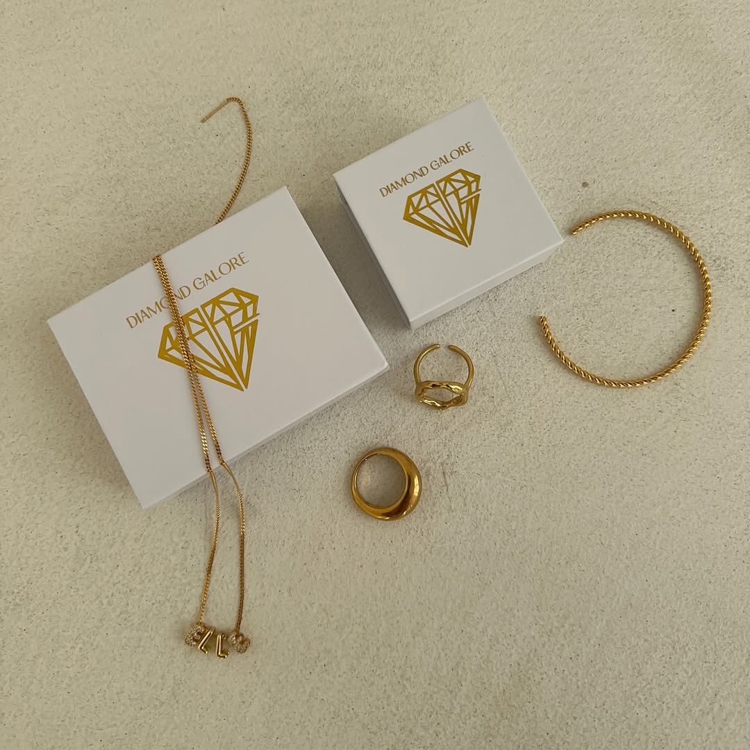 Gold jewellery set including necklace, bracelet, and rings on 'Diamond Galore' branded boxes.