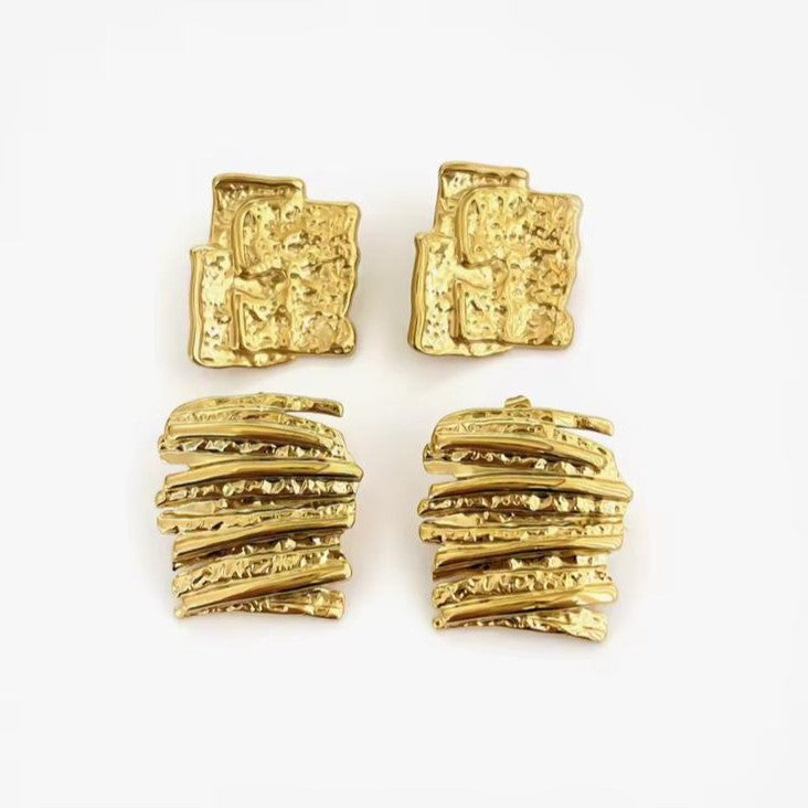 Gold textured abstract earrings on a white surface