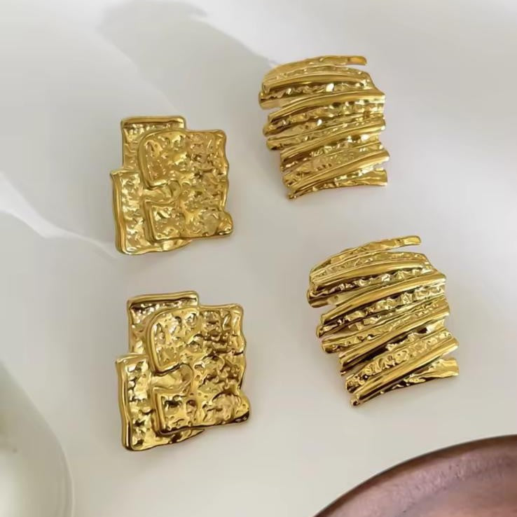 Gold textured jewelry pieces on a white surface