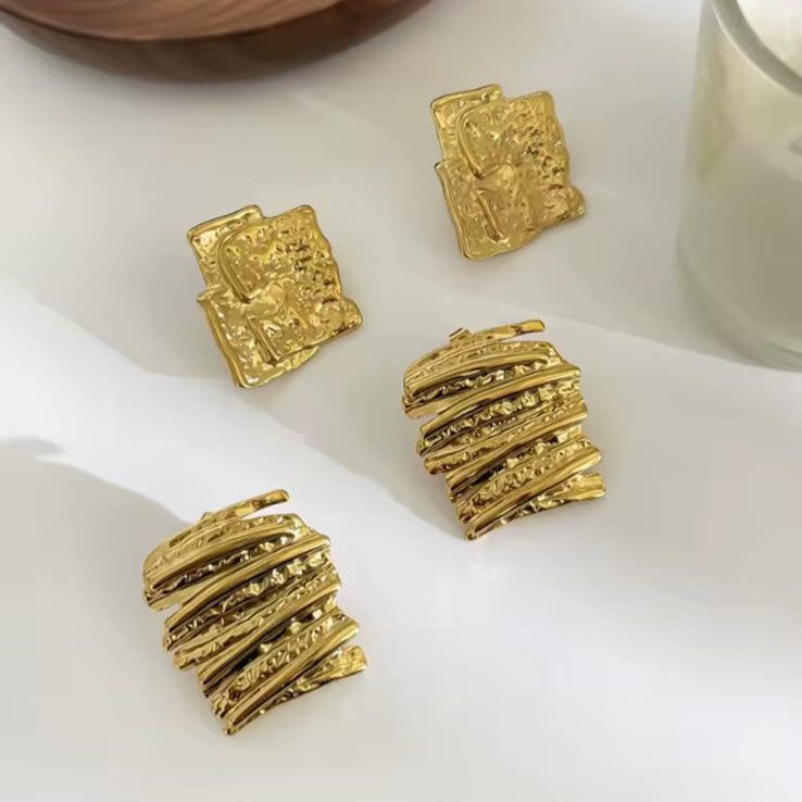 Gold earrings on a white surface on a white background
