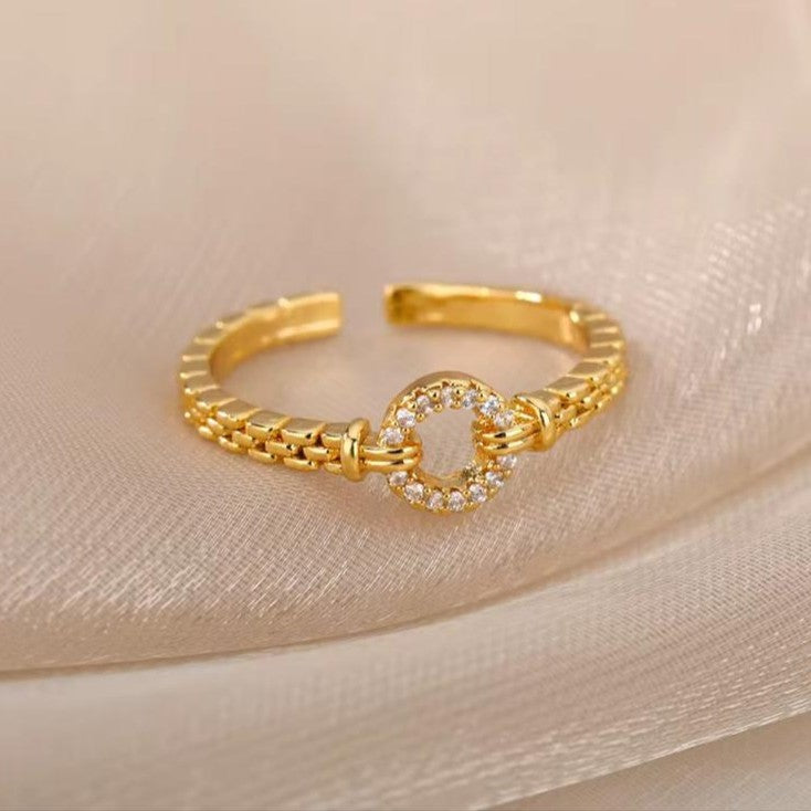 Adjustable Gold ring with heart-shaped clasp on a beige fabric background