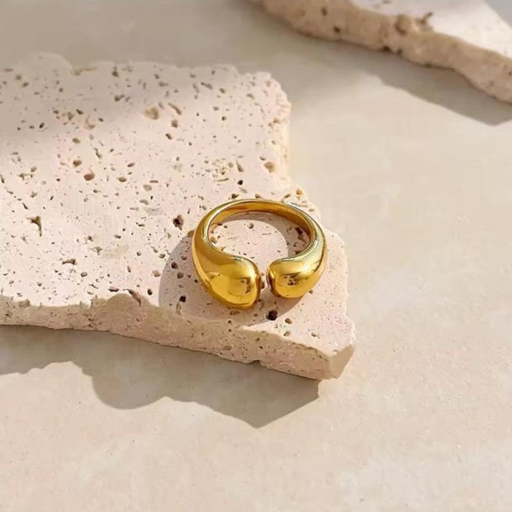 A irregular adjustable gold ring placed on a beige background. 
