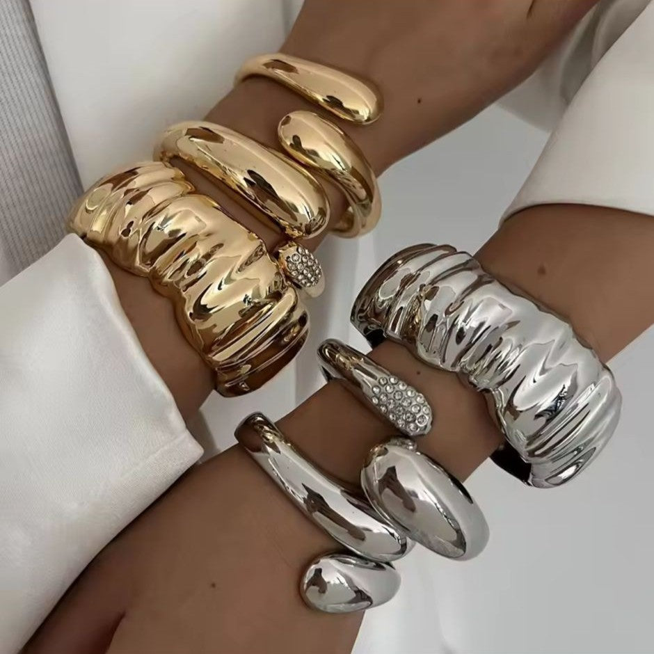 Gold and silver bracelets on a person's wrist against a white background