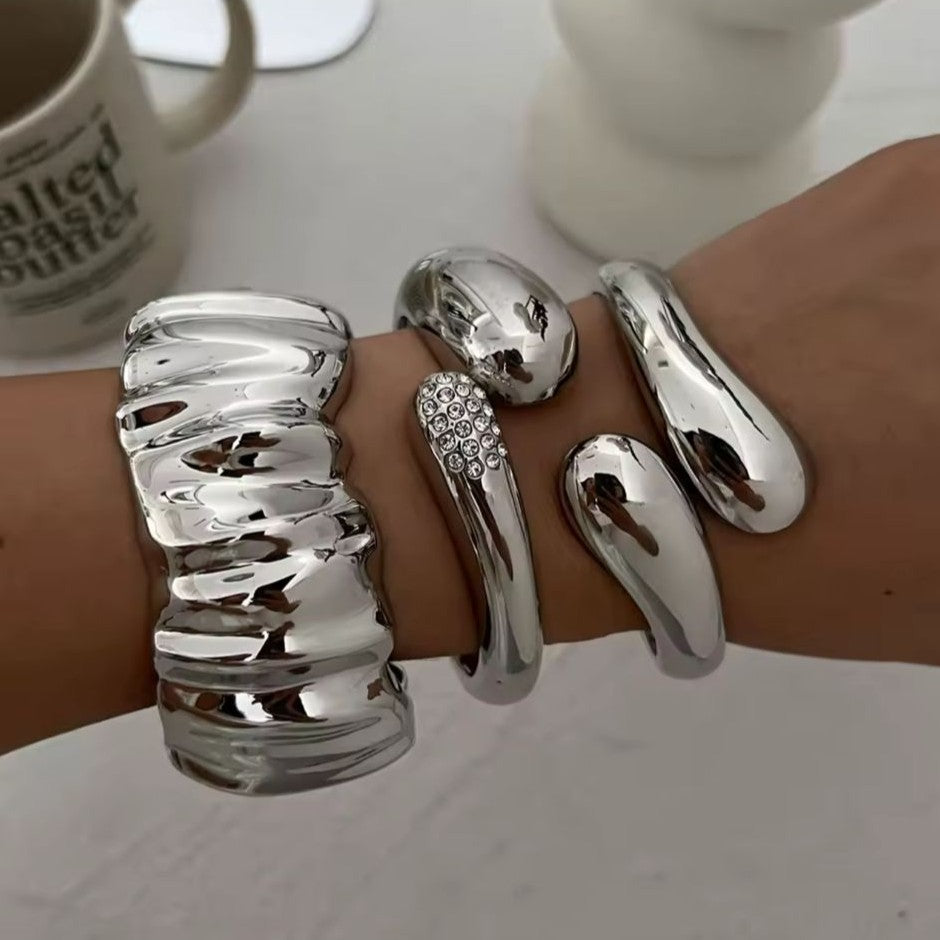 Silver bangles on a wrist with a blurred background