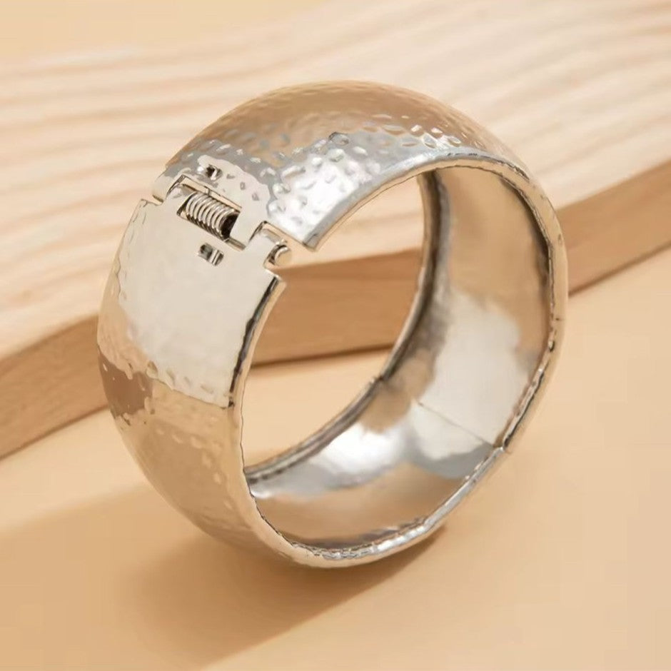 Silver Bangle with textured band on a beige surface