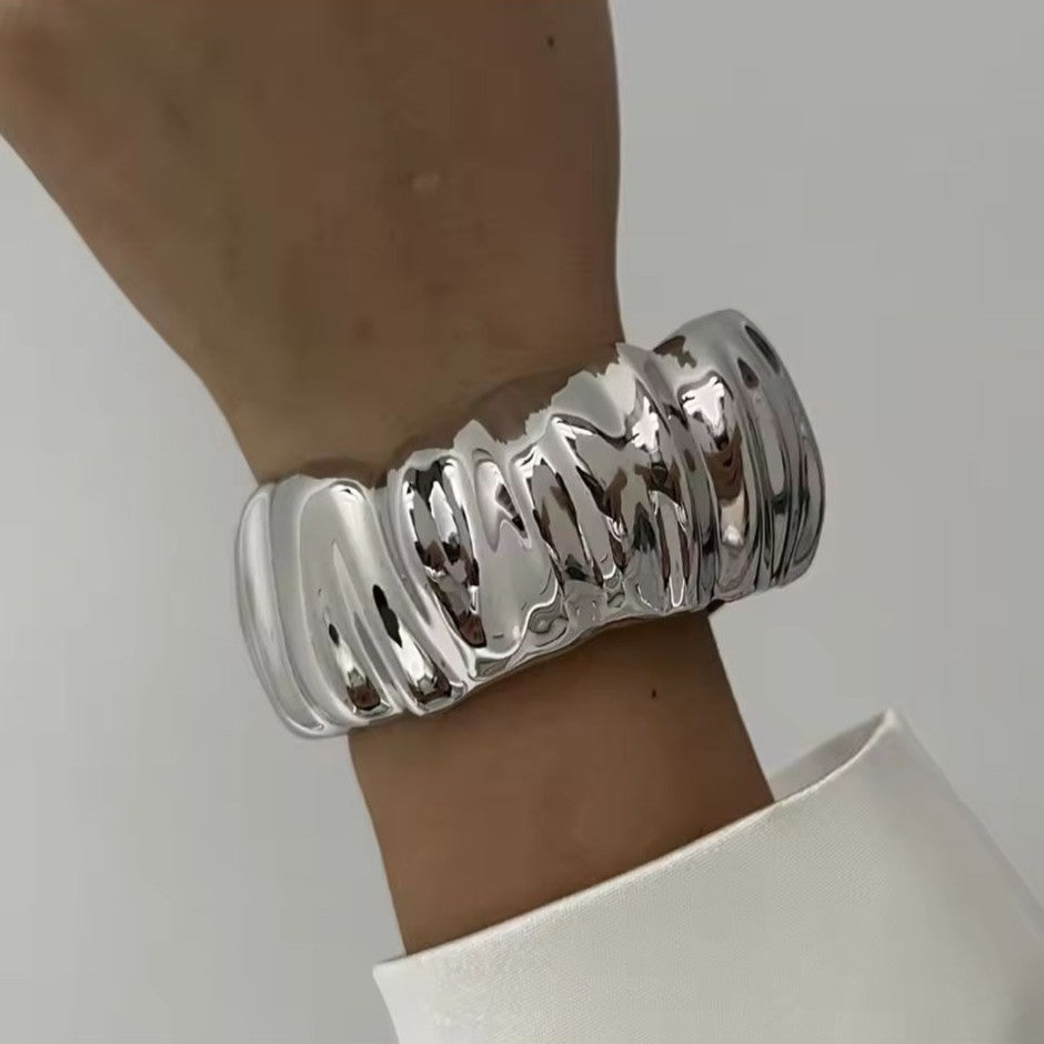 Silver bracelet on a wrist against a neutral background