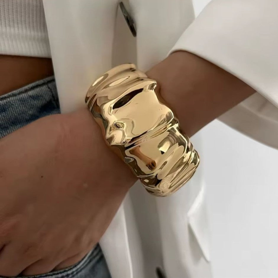 Gold bracelet on a wrist with a neutral background