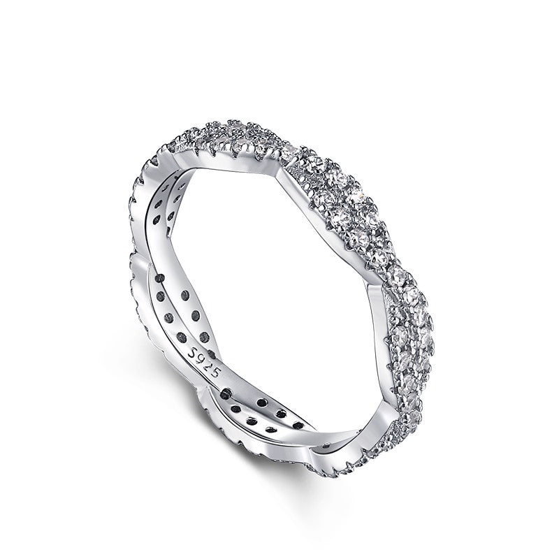 A sterling silver twist ring with multiple pave-set crystals adorning its surface on a white background.