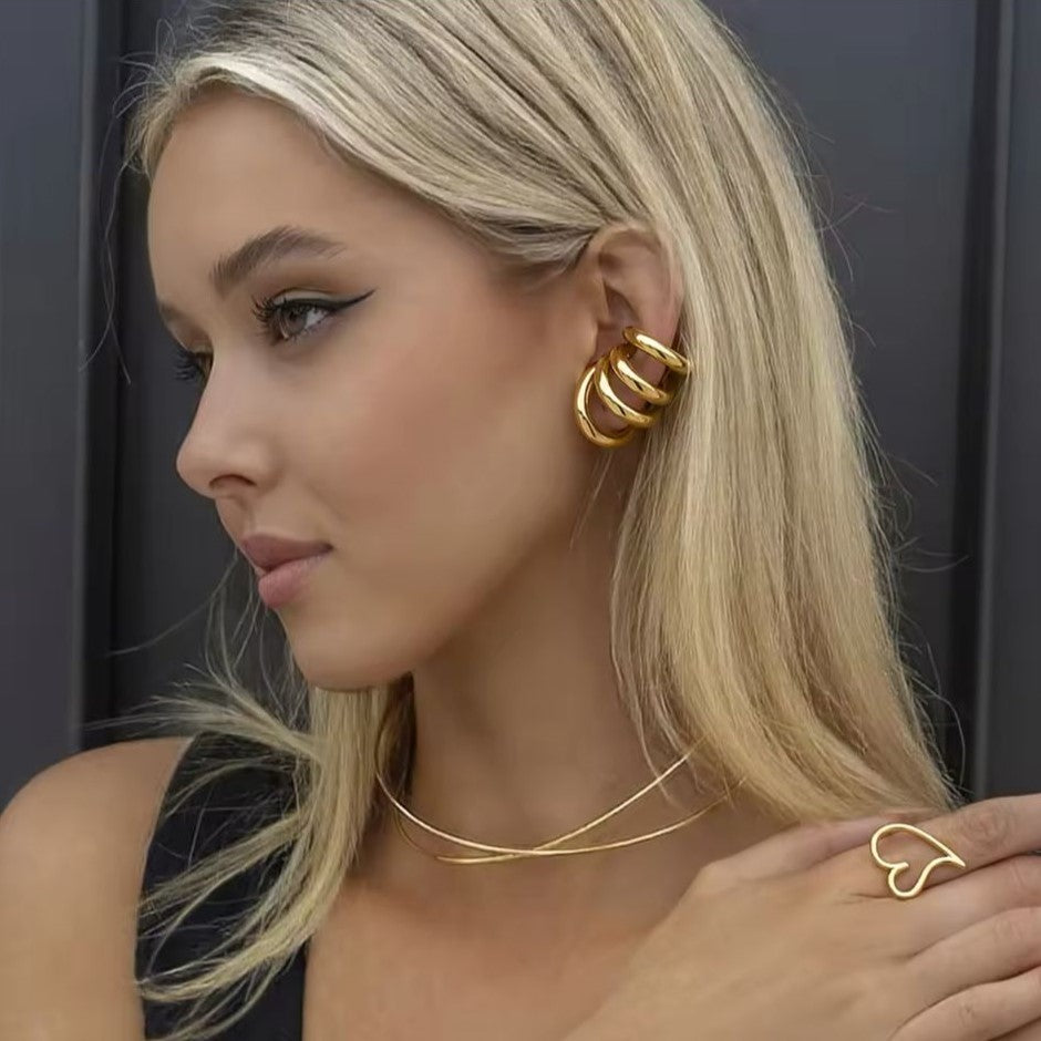 A pair of gold-colored ear cuffs with luxury design displayed on women's ear.