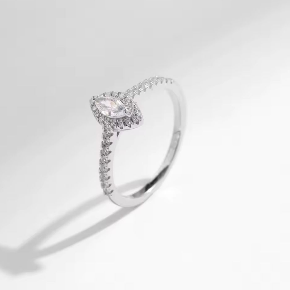 Diamond ring with marquise-shaped center stone on a neutral background