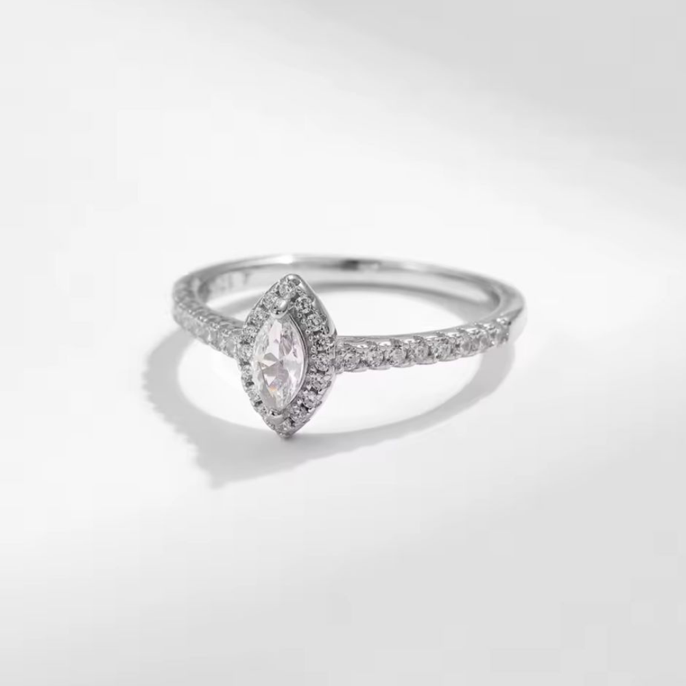 Diamond ring with a marquise-shaped center stone on a light gray background