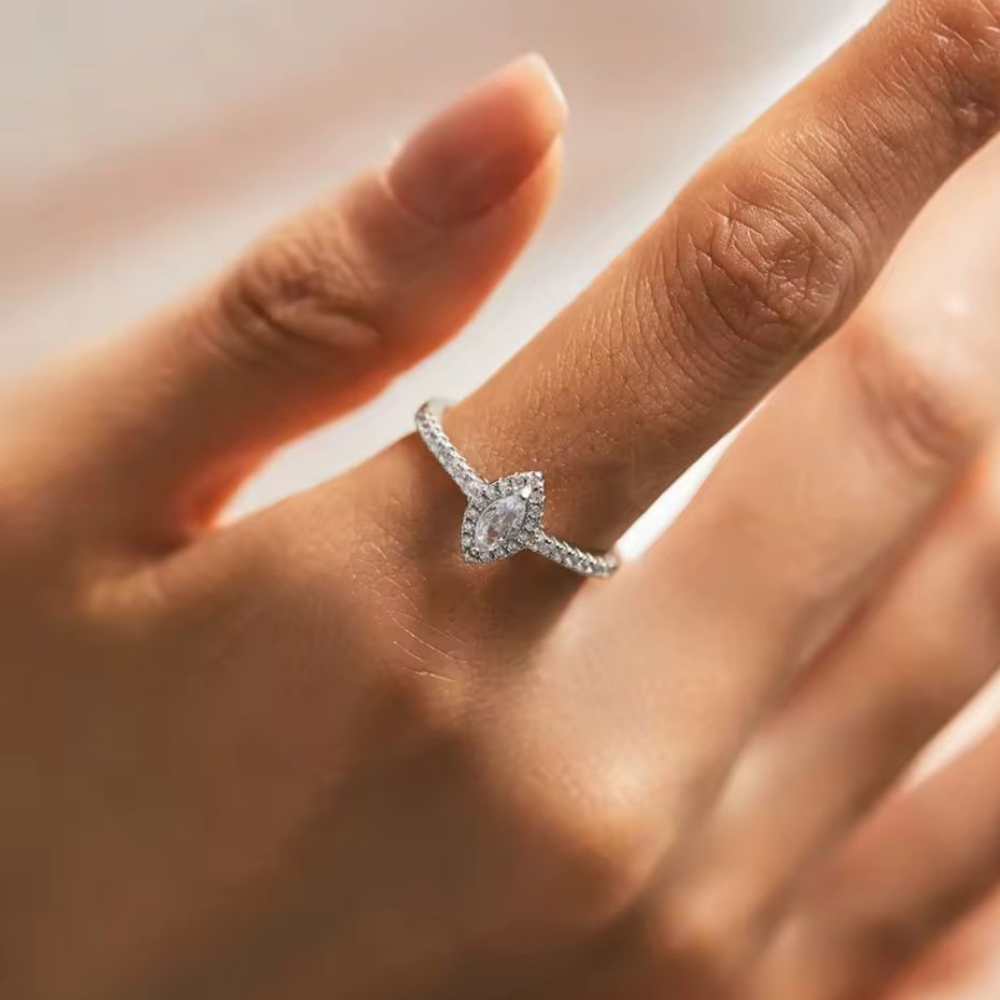 Close-up of a hand wearing a diamond ring with a blurred background