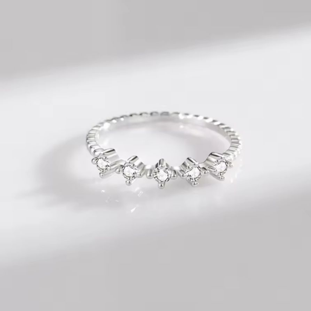 Silver ring with small diamonds on a light gray background