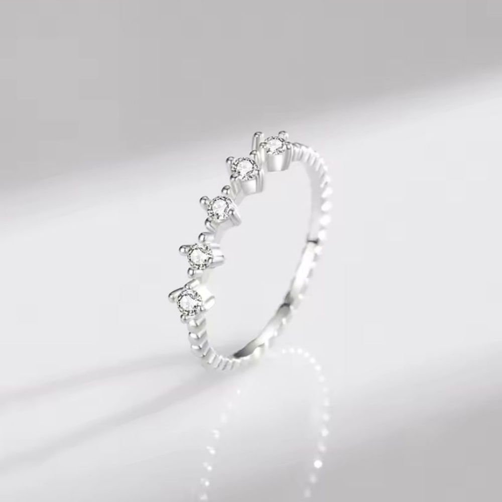 Silver ring with small diamonds on a light gray background