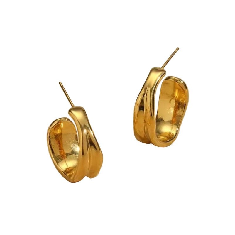 Gold hoop earrings on a textured beige surface background