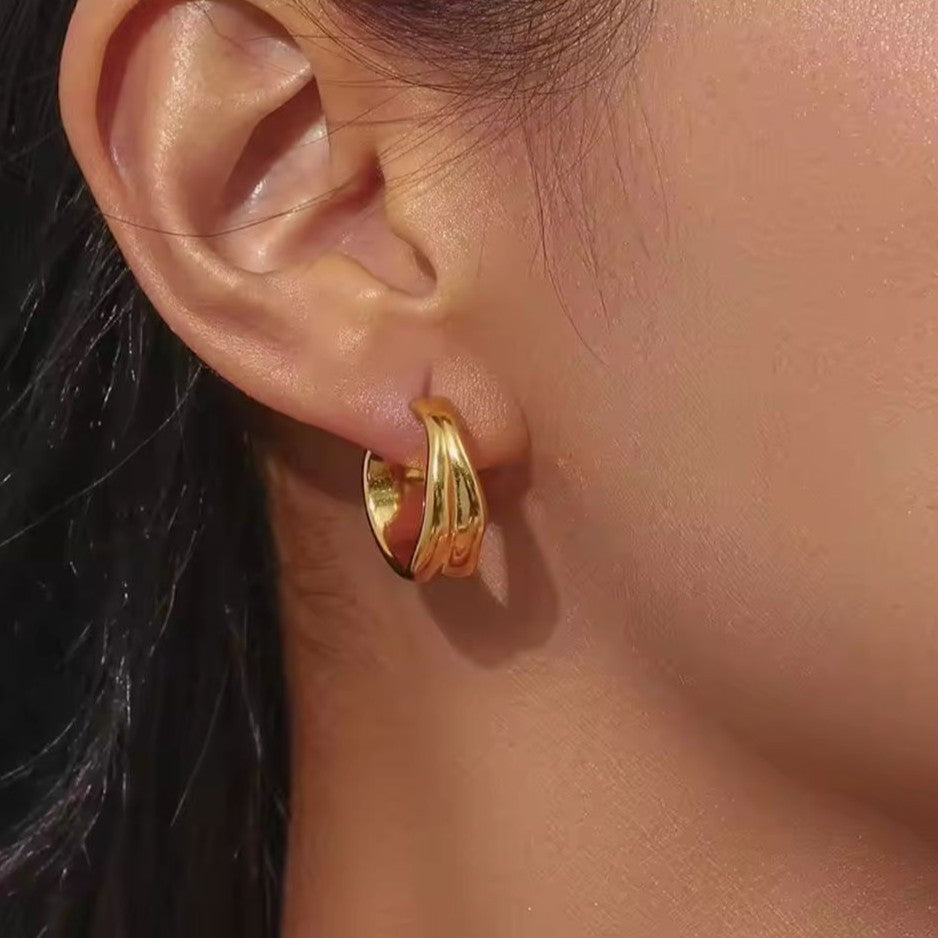 Gold hoop earring worn by a person with a blurred background