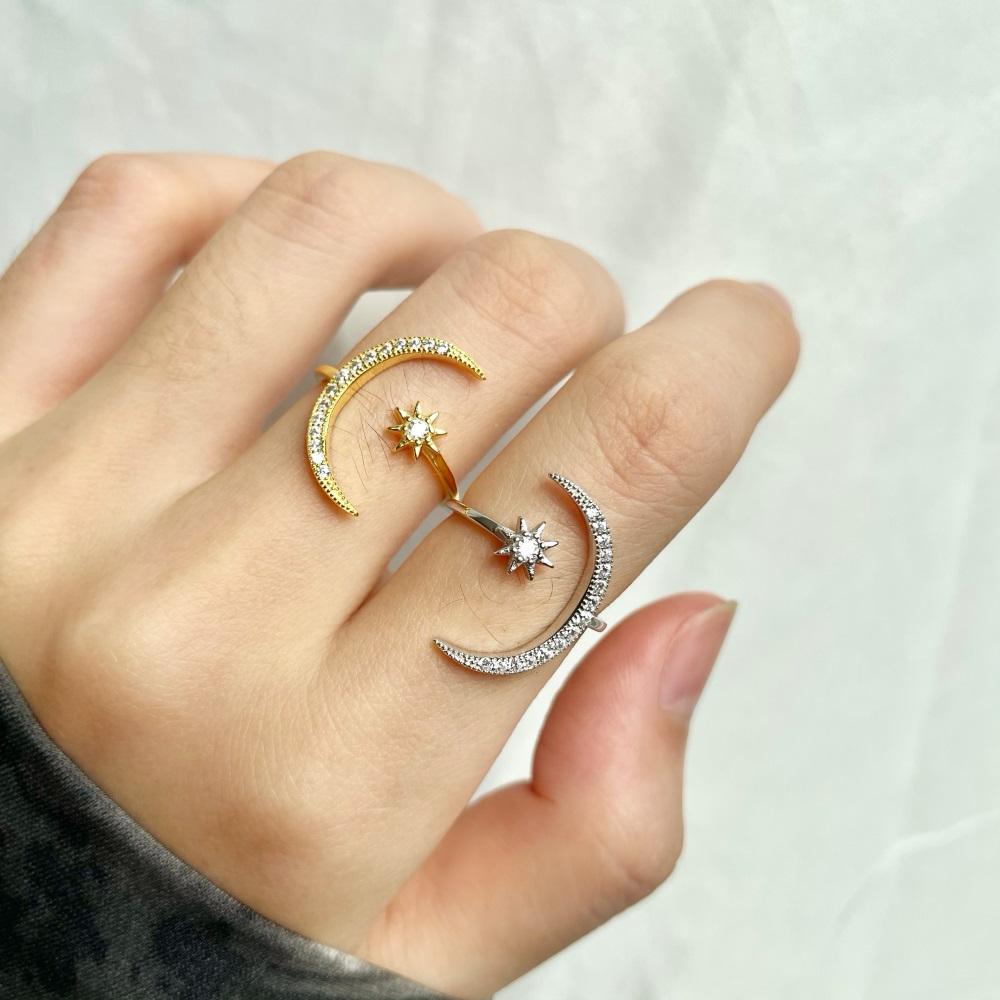 A silver & gold-colored sterling silver ring featuring a crescent moon and a star design with sparkling stones set in the moon and star shapes.
